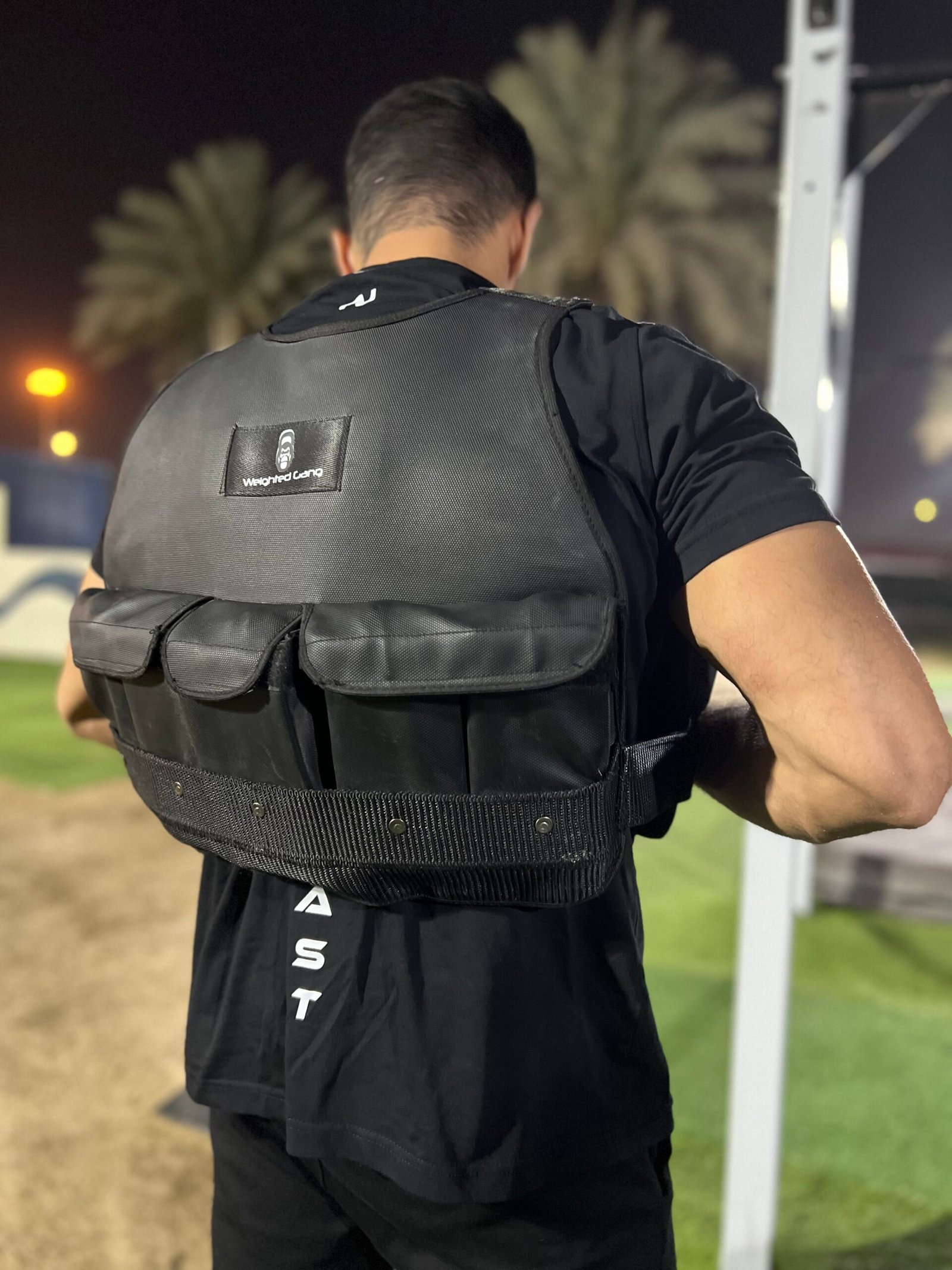 Man wearing a weighted vest during outdoor workout at night.