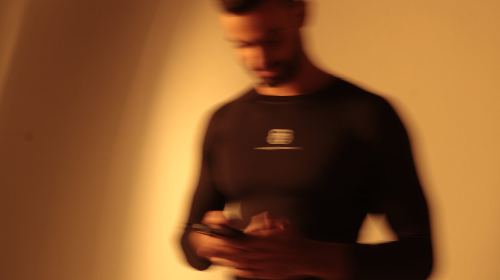 Man wearing Weighted Gang compression long sleeve shirt using a smartphone.