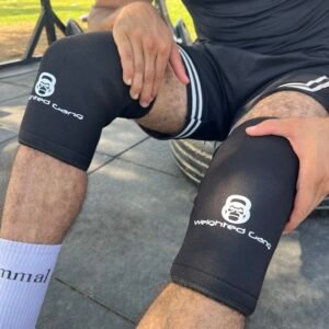 Person wearing black knee sleeves with Weighted Gang logo for knee support.