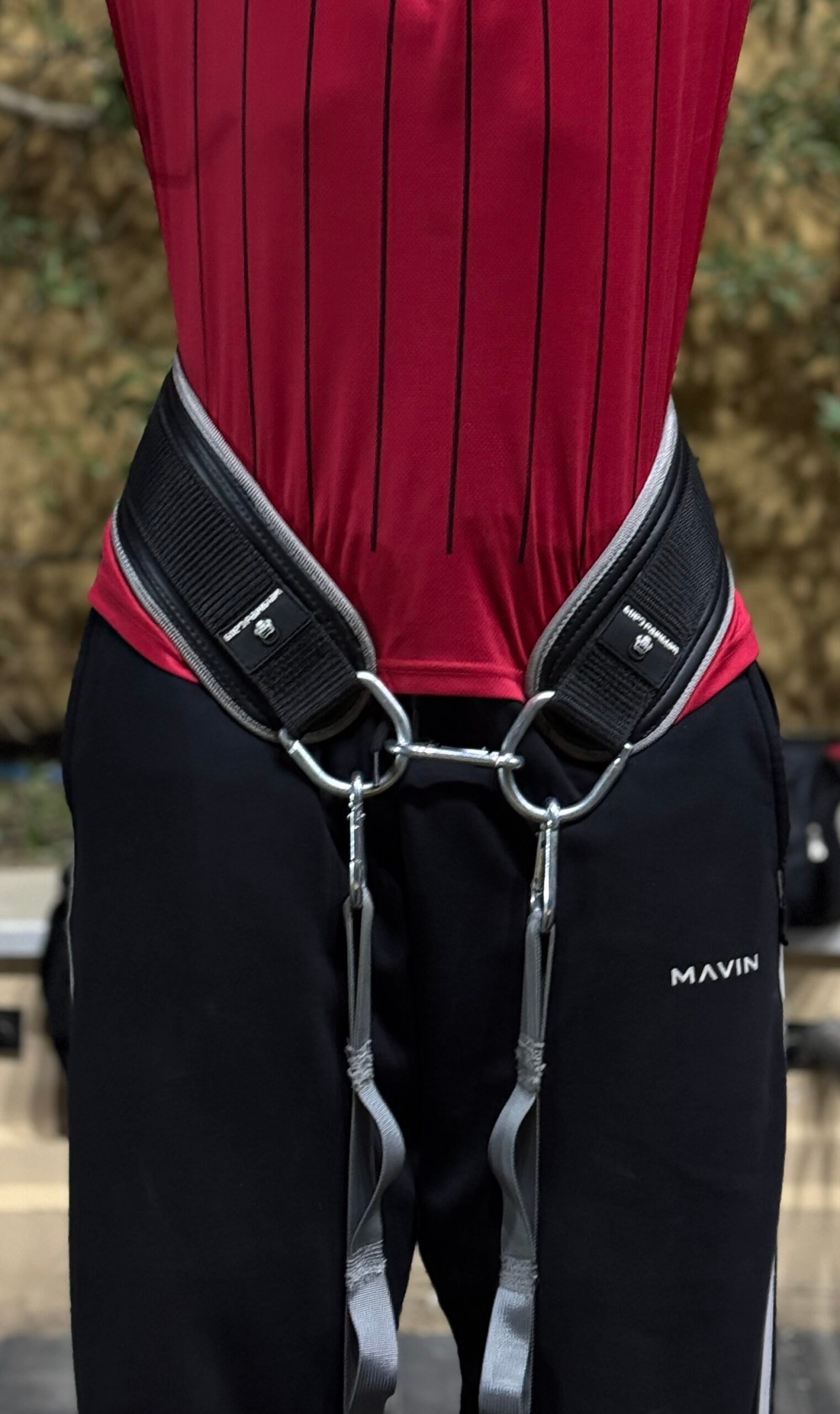 Black weighted gym belt with adjustable straps for weightlifting.
